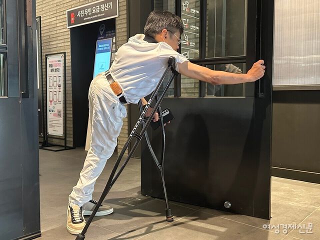 서울시 용산구에 있는 아이파크몰의 지하 주차장과 연결되는 출입구 모습. 목발을 이용하는 이성수 씨(남·62)가 여닫이문을 열고 있다. /여성경제신문