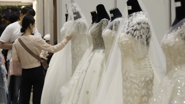 지난 2020년 7월 19일 서울 강남구 코엑스에서 열린 제54회 웨덱스코리아 웨딩박람회에서 예비 신랑 신부들이 웨딩드레스를 둘러보고 있다. /연합뉴스