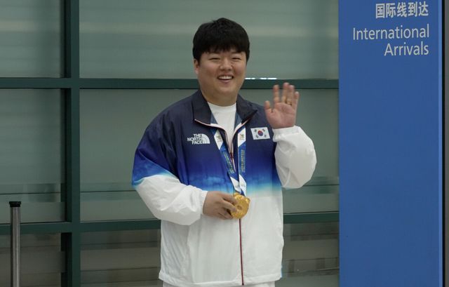 금메달을 목에 걸고 손을 흔들며 귀국하는 조명우.