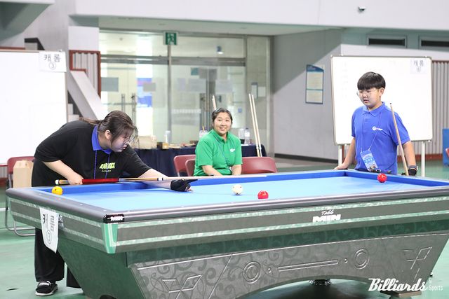 가족 단위의 참가자들이 함께 당구 경기를 즐기고 있다.