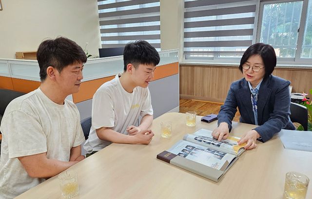 김영원(가운데)이 17일 모교 북서울중학교에서 기탁식을 가진 후 정영순 교장(오른쪽)과 졸업앨범을 보고 있다. 왼쪽은 아버지 김창수씨.
