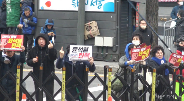 촛불시위대 인원 2명이 윤석열 지키는 사람들 측을 향해 가운뎃손가락을 들어 보이고 있다. (사진=서울미디어뉴스)