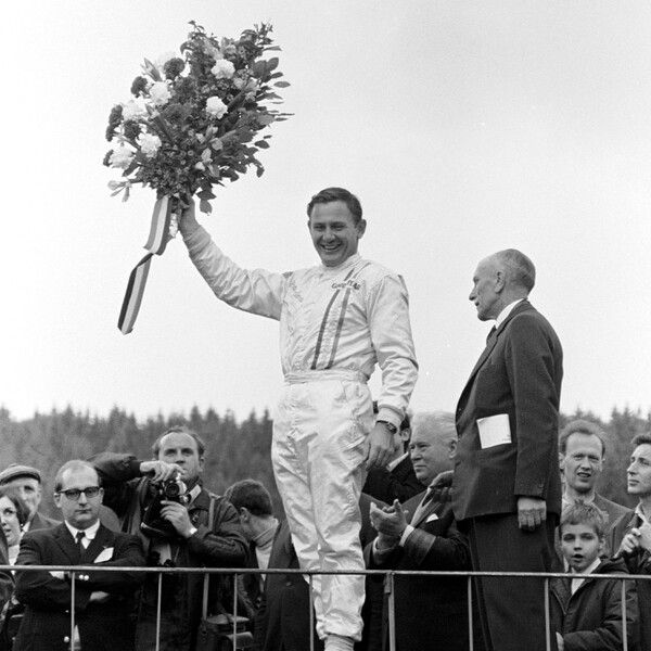 1968년 벨기에 그랑프리에서 맥라렌 팀 역사상 최초의 F1 우승을 거둔 후, 브루스 맥라렌이 시상대 위에서 꽃다발을 높이 들고 환하게 웃고 있는 장면. 사진=맥라렌 F1