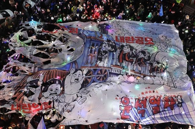 ‘윤석열 즉각 퇴진·사회대개혁 비상행동’ 주최로 13일 오후 서울 영등포구 국회의사당 인근에서 열린 탄핵소추안 국회 통과 촉구 촛불집회 참가자들이 국민의힘 당사 앞까지 행진해 현수막을 찢는 퍼포먼스를 펼치고 있다. 연합뉴스