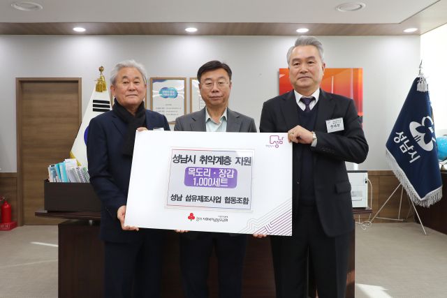 신상진 성남시장이 26일 오후한대현 성남섬유제조사업 협동조합 이사장(오른쪽)과 홍기섭 홍한섬유산업 대표(왼쪽) 등으로부터 2천만원 상당의 방한용품 1천세트를 전달받은 뒤 기념촬영을 하고 있다. 성남시 제공