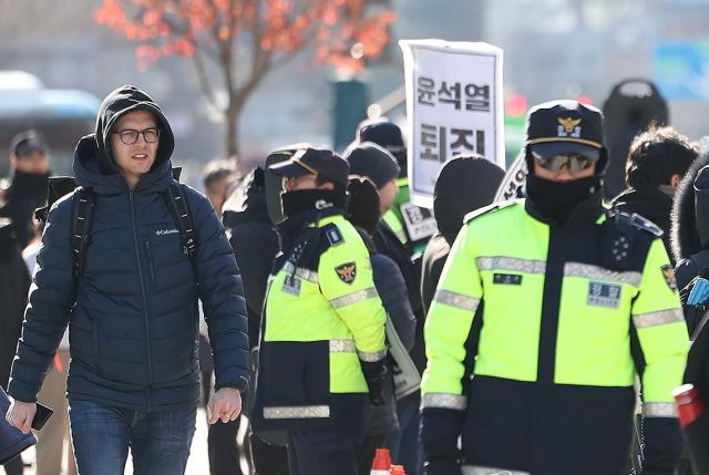 윤석열 대통령이 긴급 대국민 담화를 통해 비상계엄 해제를 선언한 4일 오전 서울 종로구 광화문광장에서 한 외국인 관광객이 계엄 규탄 집회를 지켜보고 있다.