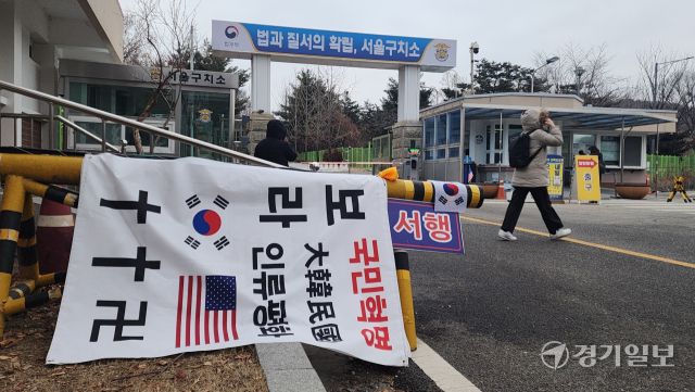 16일 오전 의왕 서울구치소 앞에 윤석열 대통령 지지자들이 태극기와 성조기가 그려진 현수막을 걸어 뒀다. . 윤석열 대통령이 지난 15일 이곳 구인피의자 대기실에서 하룻밤을 보낸 가운데 공수처는 윤 대통령이 건강상 이유로 출석 연기를 요청했다며 조사를 오후 2시부터 재개한다고 밝혔다. 윤원규기자