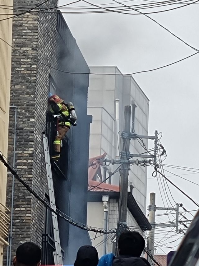 이천소방서 소방관이 이천창전동 빌라 주차장에서 발생한 화재로 빌라에 갇힌 일가족 3명을 구조하기 위해 사다리로 잡근하고 있다. 이천소방서 제공