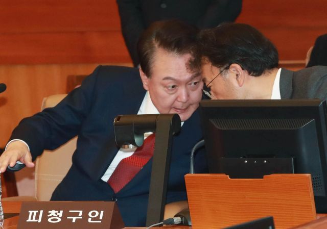 윤석열 대통령이 지난 21일 오후 서울 종로구 헌법재판소에서 열린 탄핵심판 3차 변론에 출석해 차기환 변호인과 대화하고 있다. 연합뉴스