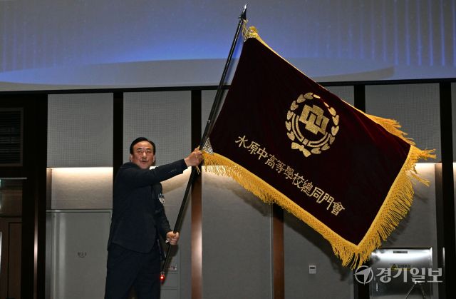 4일 오후 수원컨벤션센터에서 열린 '수원중·고등학교총동문회 2025 신년인사회, 회장 이·취임식 및 111년사 출판기념회'에서 박주왕 신임 회장이 교기를 전달받은 후 흔들고 있다. 김시범기자