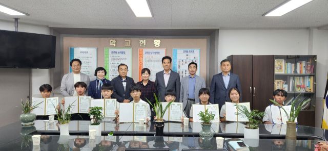 ㈔김포통진애향회 임원과 학교 교사, 학생들이 참석한 가운데, 학생들에게 전달한 장학금 증서를 보이며 기념사진을 촬영하고 있다. ㈔김포통진애향회 제공