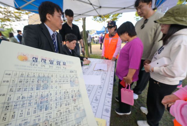 16일 의왕시 왕송호수공원 잔디광장에서 열린 '제46회 흰지팡이날 및 제99회 점자의날 기념 경기도시각장애인복지복지대회'에서 시민들이 점자 명함을 만들고 있다. 윤원규기자