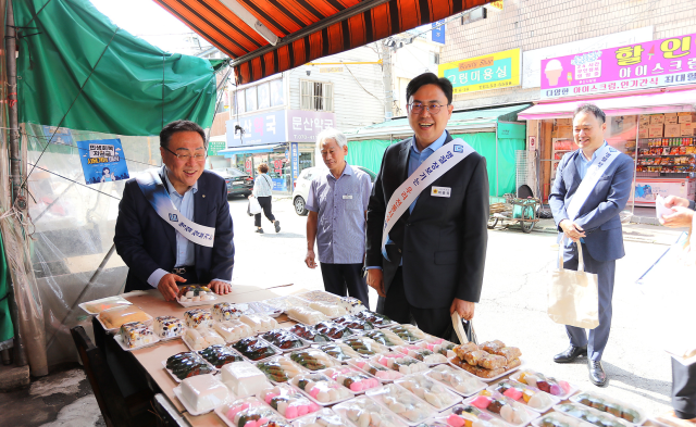 시석중 경기신용보증재단 이사장(왼쪽)과 이용욱 경기도의원(오른쪽)이 2일 파주 전통시장을 찾아 제수용품을 구입하고 있다. 경기신보 제공.