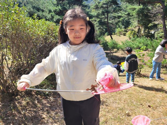 신지초교 1학년 여학생이 구운 고구마를 친구들과 나눠먹기 위해 들고 가고 있다. 신지초교 제공