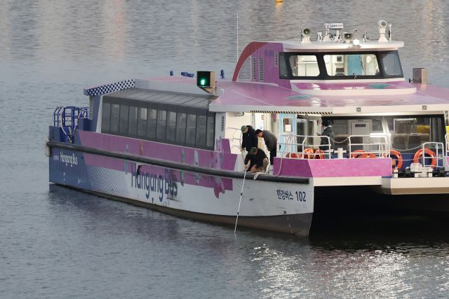 16일 서울 송파구 잠실선착장 부근 강바닥에 걸려 멈춘 한강버스에서 관계자가 수심 확인을 하고 있다. 연합뉴스