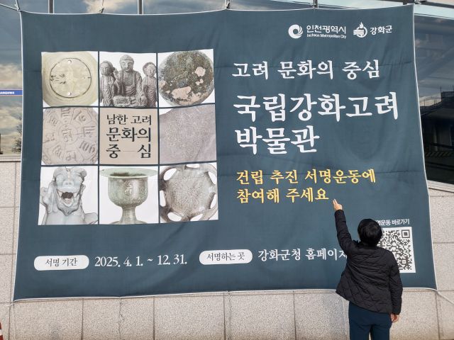 국립강화고려박물관 건립을 위한 ‘기본계획 수립 용역비’가 국회 문화체육관광위원회를 통과했다는 소식에 한 강화 주민이 군청사 앞에 내걸린 박물관 유치 운동 현수막을 가리키고 있다. 조향래 기자