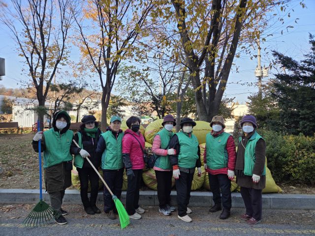 사우동 새마을부녀회 회원들이 환경정화 활동을 마친 후, 수거한 쓰레기더미 앞에서 기념사진을 촬영하고 있다. 사우동 행정복지센터 제공