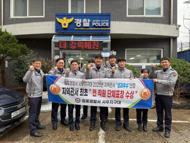 문흥주 지구대장(왼쪽 세 번째)과 대원들이 지역관서 최초 ‘전 직원 단체표창’을 축하하는 현수막을 보이며 화이팅을 외치고 있다. 사우지구대 제공