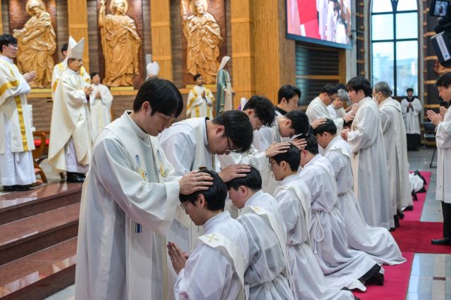 교구장 이용훈 마티아 주교가 사제단과 안수를 통해 후보자들을 축복하고 있다.