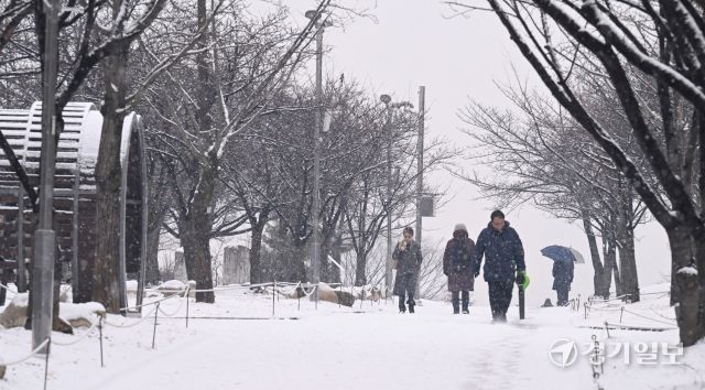12일 인천 남동구 중앙공원에서 시민들이 눈을 맞으며 발걸음을 옮기고 있다.조병석 기자