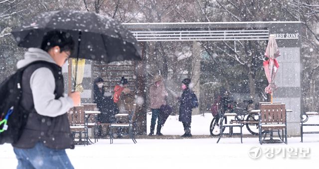 12일 인천 남동구 중앙공원에서 시민들이 눈을 맞으며 발걸음을 옮기고 있다.조병석 기자