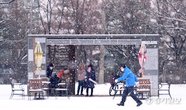 12일 인천 남동구 중앙공원에서 시민들이 눈을 맞으며 발걸음을 옮기고 있다.조병석 기자
