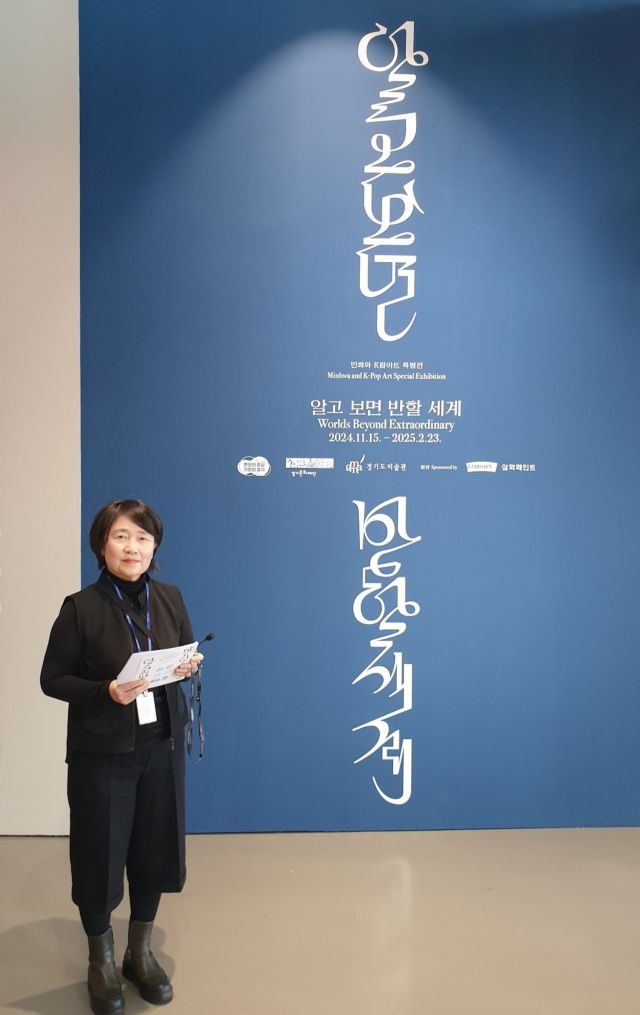 경기도미술관의 문화자원봉사자로 임하고 있는 이현희씨(64)가 전시해설 투어를 맡은 “민화와 K팝아트 특별전 ‘알고 보면 반할 세계’” 전시장 앞에 서 있다. 본인 제공