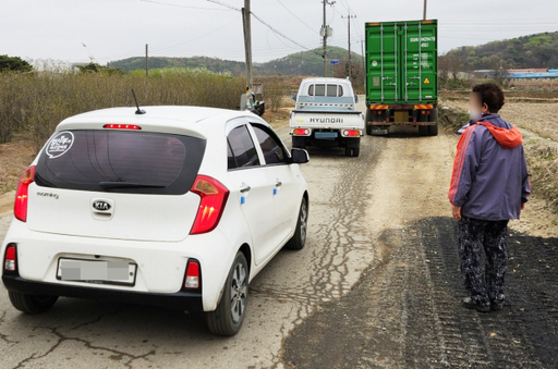 인천 서구 불로대곡동 대곡로에 보도가 없어 한 주민이 차와 함께 걷고 있다. 경기일보 DB