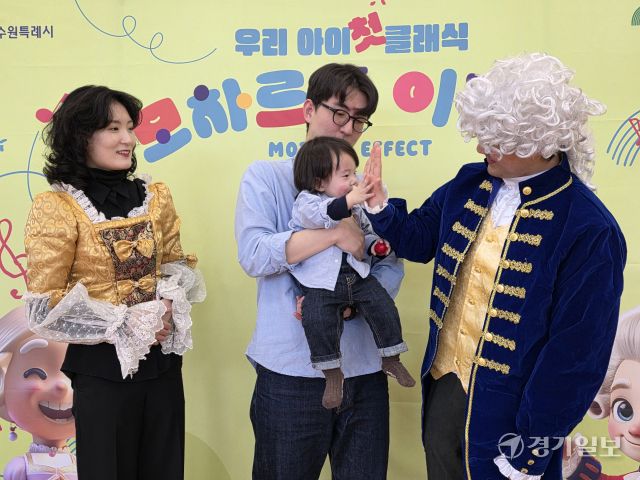 이날 프로그램에 자리한 정이든군(14개월)이 모차르트 역의 배우와 손을 맞대며 기념촬영을 하고 있다. 이나경기자