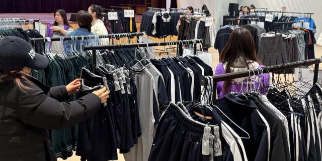 8일 구리시청 대강당에서 열린 ‘구리알뜰교복은행' 집중 판매행사에서 학부모와 학생들이 교복을 고르고 있다. 구리지역 16개 중·고등학교 졸업생들이 기증한 교복 5천600점은 세탁과 수선을 거쳐 5천원 이하의 저렴한 가격으로 판매됐다.조주현기자