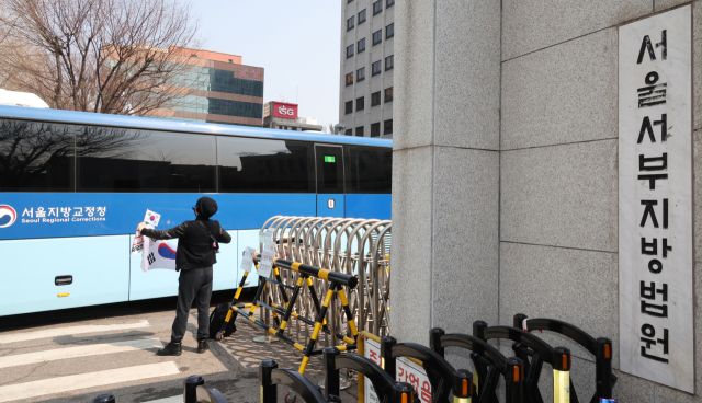 '서부지법 난동 사태' 첫 재판이 열린 10일 서울 마포구 서울서부지방법원에서 한 보수단체 회원이 호송버스를 향해 태극기를 들어보이고 있다. 연합뉴스