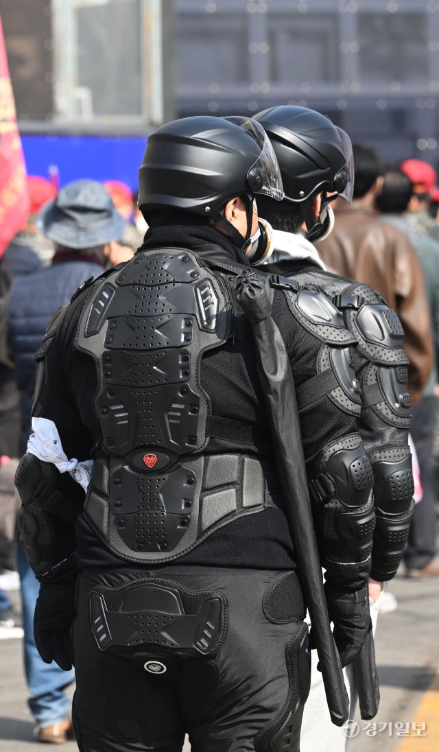 헌법재판소의 윤석열 대통령 탄핵 심판 선고일인 4일 오전, 헌법재판소 인근 폴리스라인 앞에서 전투 헬멧과 전술복 등을 착용한 시민들이 어깨에 기다란 물건을 검은 가방에 담아 이동하고 있다.조주현 기자