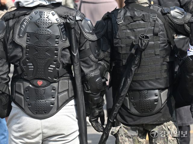 헌법재판소의 윤석열 대통령 탄핵 심판 선고일인 4일 오전, 헌법재판소 인근 폴리스라인 앞에서 전투 헬멧과 전술복 등을 착용한 시민들이 어깨에 기다란 물건을 검은 가방에 담아 이동하고 있다.조주현 기자