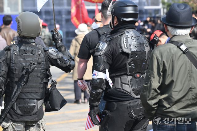 헌법재판소의 윤석열 대통령 탄핵 심판 선고일인 4일 오전, 헌법재판소 인근 폴리스라인 앞에서 전투 헬멧과 전술복 등을 착용한 시민들이 어깨에 기다란 물건을 검은 가방에 담아 이동하고 있다.조주현 기자
