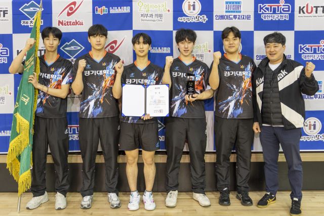 제43회 한국대학탁구연맹전에서 2년 만에 남자부 단체전 패권을 되찾는 등 3개 종목을 석권한 경기대 이재욱 감독(오른쪽)과 선수들이 우승기를 앞세우고 기념촬영을 하고 있다.월간탁구 제공