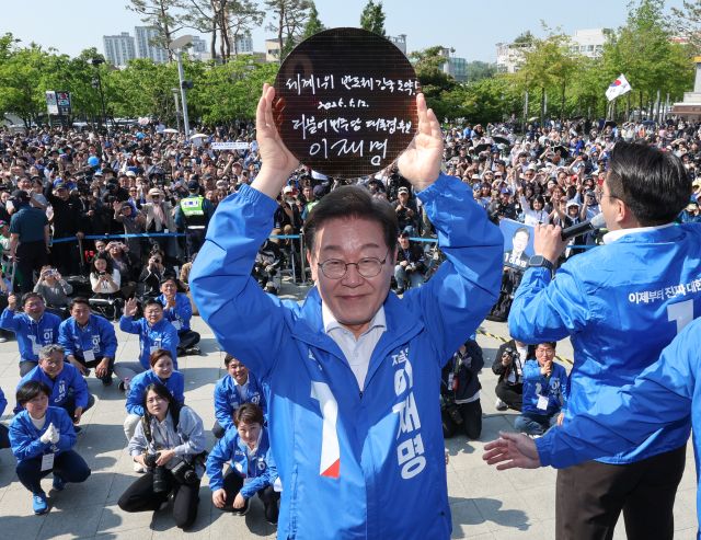 더불어민주당 이재명 대선 후보가 6·3 대통령선거 공식 선거운동 첫날인 12일 경기 화성시 동탄 센트럴파크 음악분수중앙광장 유세장에서 '세계1위 반도체 강국 도약!'이라고 쓰고 서명한 반도체 웨이퍼를 들어보이고 있다. 연합뉴스