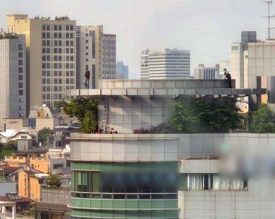 13일 서울 지하철 2호선 강남역 인근 빌딩 옥상에서 한 남성이 투신 소동을 벌여 경찰관과 구조대원들이 구조를 위해 접근하고 있다. 연합뉴스