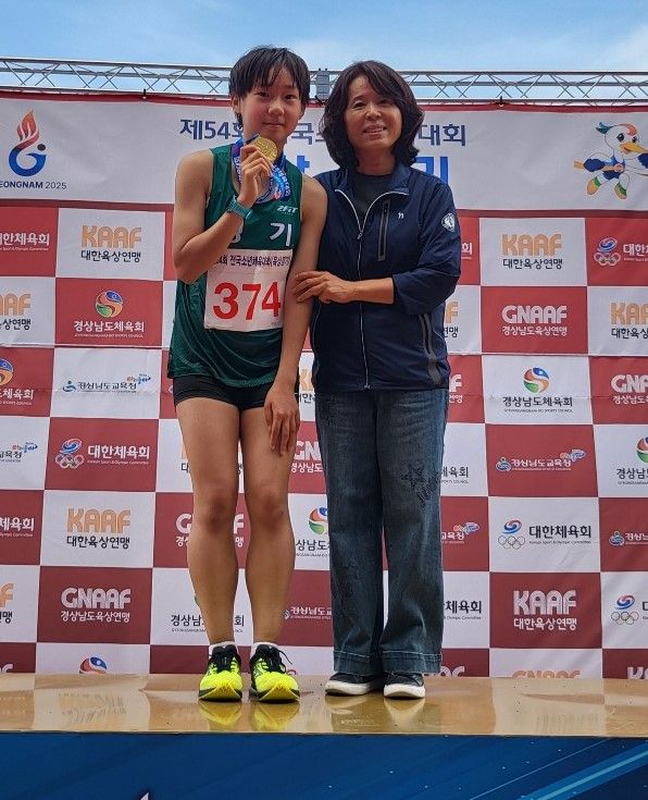 제54회 전국소년체전 육상 여중부 5천m 경보서 우승한 정채연이 김연주 교장과 기념촬영을 하고 있다.철산중 제공