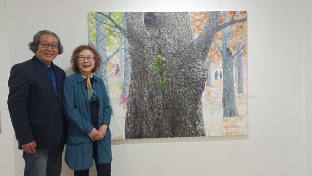 17일 예술공간 아름에서 권용택·이향재 부부가 자신들의 뒷모습이 그려진 권 씨의 작품 ‘느릅나무이야기’ 앞에서 함께 사진을 찍고 있다. 정자연기자