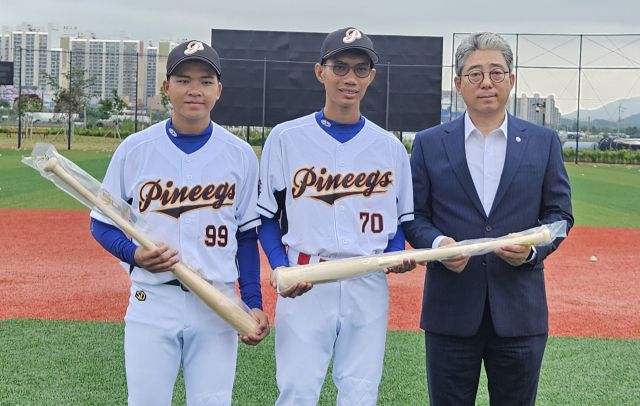 곽영붕 수원BC 이사장(오른쪽)이 22일 수원파인이그스 훈련장에서 3개월 간 위탁 교육을 온 라오스 야구대표팀 태오(왼쪽)와 나에게 배트를 선물하고 있다.수원BC 제공