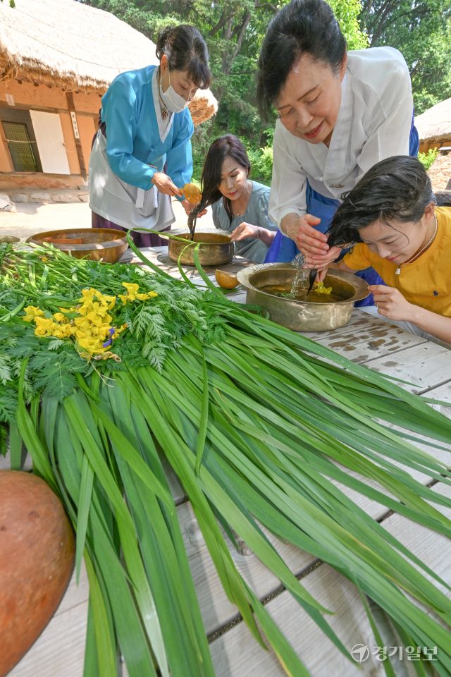 단오를 이틀 앞둔 29일 오전 용인특례시 한국민속촌에서 관광객들이 창포물에 머리감기 체험을 하고 있다. 수릿날·천중절·단양 이라고도 불리는 단오에는 남자는 씨름을 하고 여자는 창포물에 머리를 감거나 그네를 뛰며 하루를 보낸다. 김시범기자