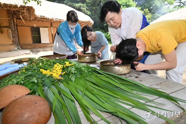 단오를 이틀 앞둔 29일 오전 용인특례시 한국민속촌에서 관광객들이 창포물에 머리감기 체험을 하고 있다. 수릿날·천중절·단양 이라고도 불리는 단오에는 남자는 씨름을 하고 여자는 창포물에 머리를 감거나 그네를 뛰며 하루를 보낸다. 김시범기자