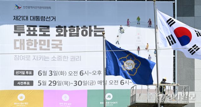 제21대 대통령선거를 27일 앞둔 7일 인천시 미추홀구 인천시 선거관리위원회 외벽에 작업자들이 대선 투표일과 사전 투표일을 알리는 대형 현수막을 설치하고 있다. 조병석기자