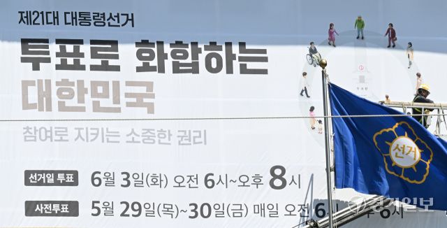 제21대 대통령선거를 27일 앞둔 7일 인천시 미추홀구 인천시 선거관리위원회 외벽에 작업자들이 대선 투표일과 사전 투표일을 알리는 대형 현수막을 설치하고 있다. 조병석기자