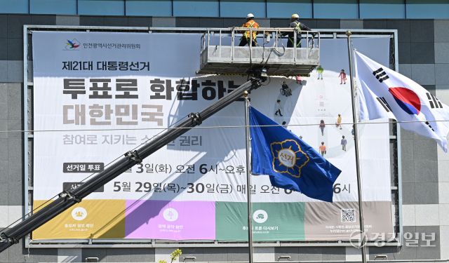 제21대 대통령선거를 27일 앞둔 7일 인천시 미추홀구 인천시 선거관리위원회 외벽에 작업자들이 대선 투표일과 사전 투표일을 알리는 대형 현수막을 설치하고 있다. 조병석기자