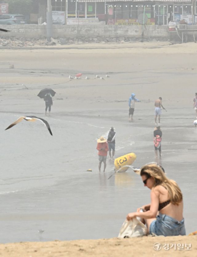 무더운 날씨를 보인 18일 오후 인천 을왕리 해수욕장에 짙은 해무가 깔린 가운데 피서객들이 물놀이를 즐기고 있다. 조병석기자 .