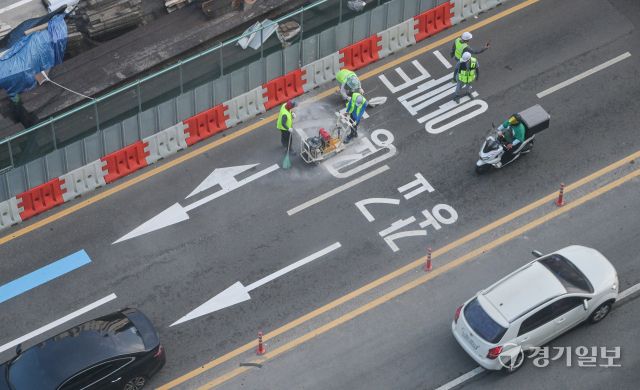 수원특례시 장안구 복합쇼핑몰 스타필드 수원 앞 대로에 ‘광교’ 방면임을 나타내는 도로노면표지가 엉터리 한글로 표기돼 있어 시의 부실한 도로 관리 실태가 도마에 오르고 있다. ‘가’ 사이에 ㅎ자가 ㅗ,ㅏ,ㅇ 자를 대체하며 ‘광’자, ㄱ자와 ㅛ 자가 기괴하게 조합된 ‘교’ 자로 돼있다. 사진은 지난 8일 오후 6시5분께 작업자가 문제의 표기를 지우고 있는 모습. 윤원규기자
