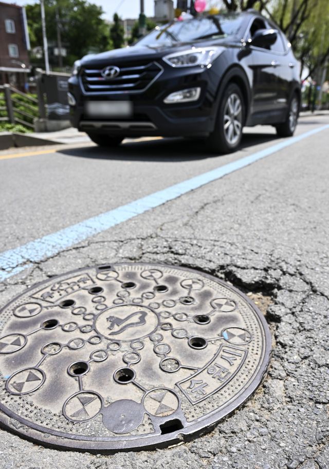 한 도로에 파손 및 침하된 맨홀 위로 차량이 다니고 있다. 경기일보DB
