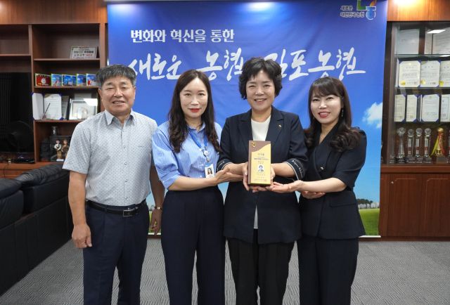 김명희 조합장(오른쪽 두번째)과 직원들이 상반기 ‘통합 마케팅 프로모션’ 평가에서 수상한 최우상 상패를 들고 기뻐하며 기념사진을 촬영하고 있다. 김포농협 제공