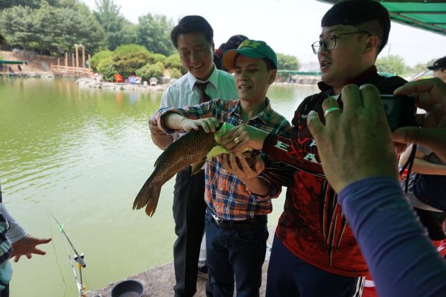 낚시 봉사에 참여한 시각 장애인이 잡은 물고기를 만지고 있다. 초록우산 인천지역본부제공